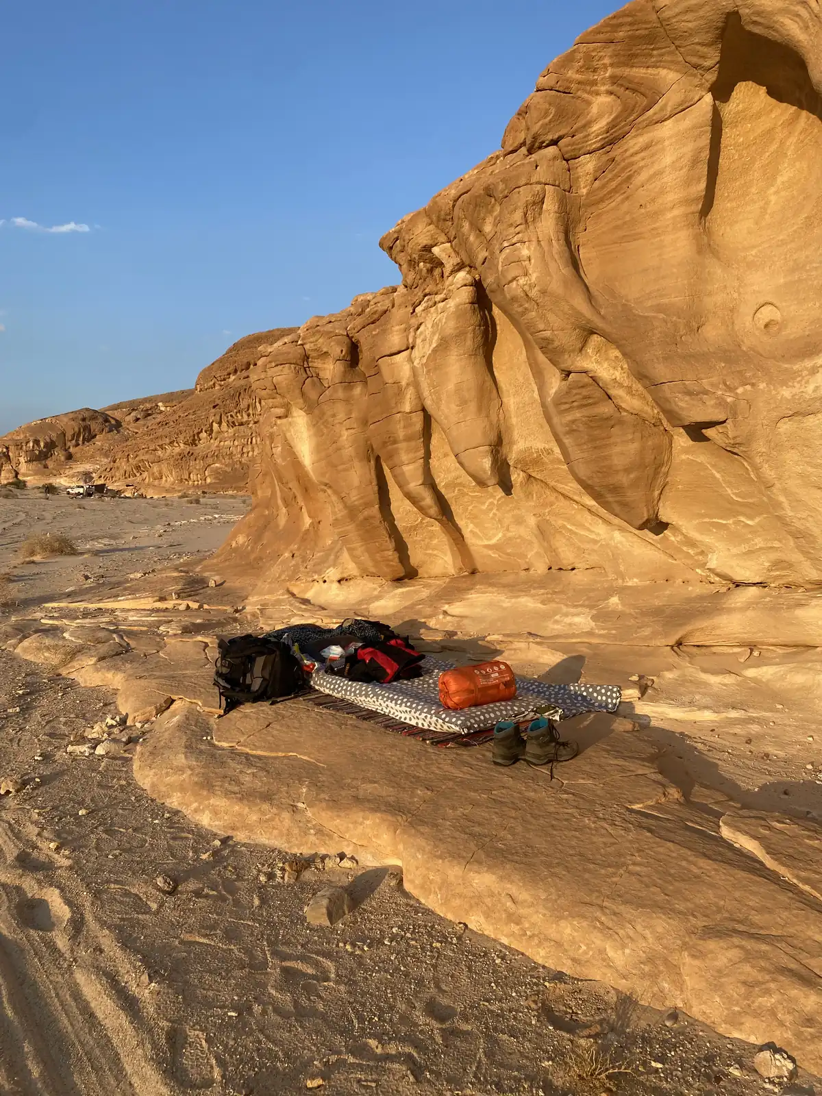 Schlafsack und Rucksack liegen unter freiem Himmel an goldenen Sandsteinfelsen in der Wüste