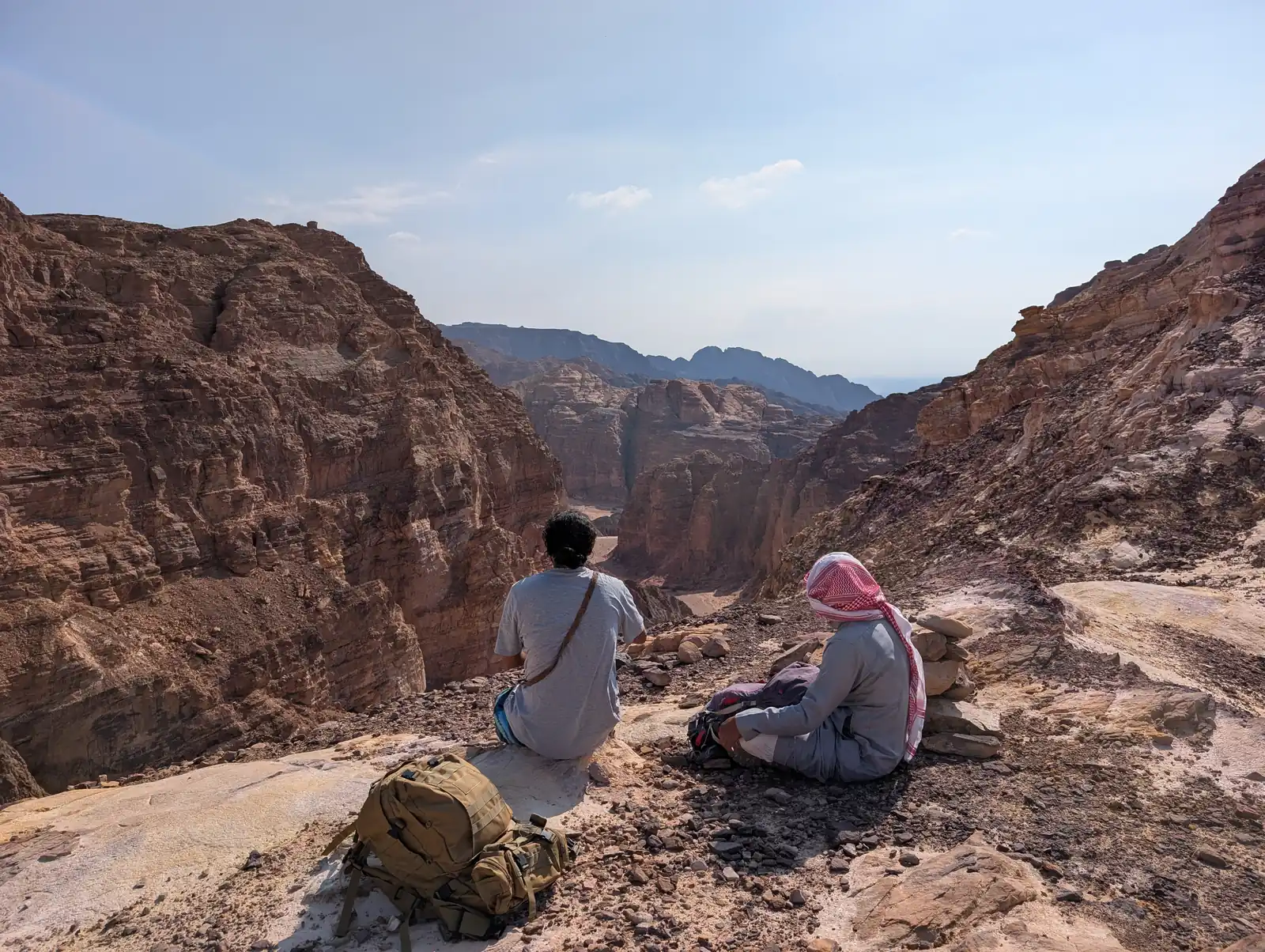 Zwei Personen sitzen auf Fels und blicken in den weiten Canyon des Süd-Sinai