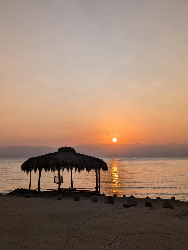 Sonnenuntergang über dem Roten Meer im Sinai mit Palmenhütte am Strand